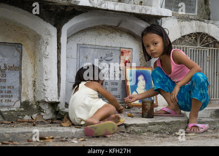 Due bambini piccoli giocano all'interno del cimitero di Carreta, Cebu City, Filippine, sull'approccio a tutti i Santi, All Souls Day Foto Stock