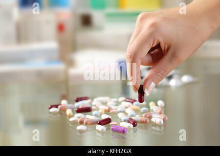 In prossimità di una donna mano la cattura di una pillola da un gruppo di farmaci su un tavolo di vetro Foto Stock