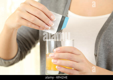 In prossimità di una donna preparare un sacchetto mucolitico la medicina in un bicchiere di acqua Foto Stock