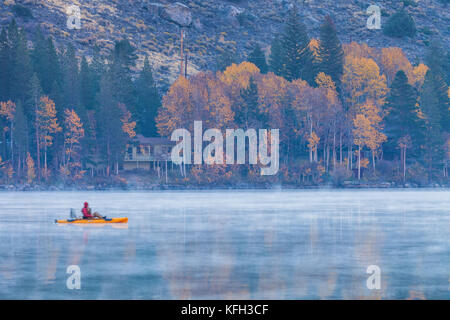 Un pescatore di canottaggio sul Lago d'argento, che copriva con nebbia, su un inizio autunno mattina, Giugno Lago di Loop, Giugno Lago, California. Foto Stock