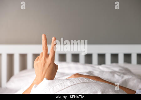 La donna solleva due dita fino a portata di mano sul letto mostrano che si dovrebbe dare il benvenuto al nuovo mattino. Foto Stock