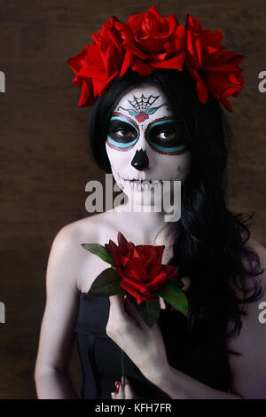 Il giorno dei morti. halloween. giovane donna nel giorno dei morti maschera viso cranio arte e rosa scuro dello sfondo. Foto Stock