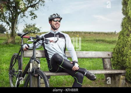 Ciclista prendendo una pausa su un banco di lavoro Foto Stock