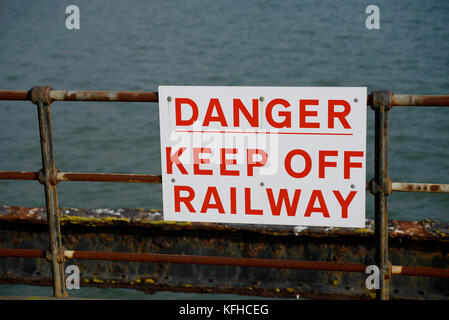 Cartello di avvertimento Southend Pier Railway, pericolo tenere lontano dalla ferrovia sulle ringhiere. Corrosione Foto Stock