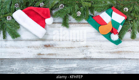 Bordo superiore della struttura ad albero di natale Abete rami, santa e elf cappelli su legno rustico nel piatto formato laici Foto Stock