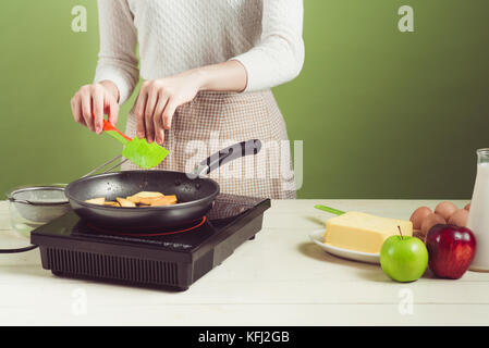 Casa moglie indossando il grembiule rendendo. fasi di realizzare la cottura di torta di mele. Il taglio di mela verde. Foto Stock