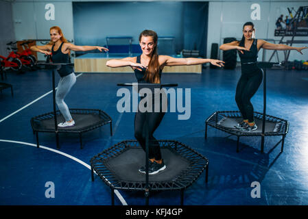 Gruppo di donne sullo sport trampolino, fitness training. Il lavoro di squadra femminile in palestra. classe di aerobica Foto Stock