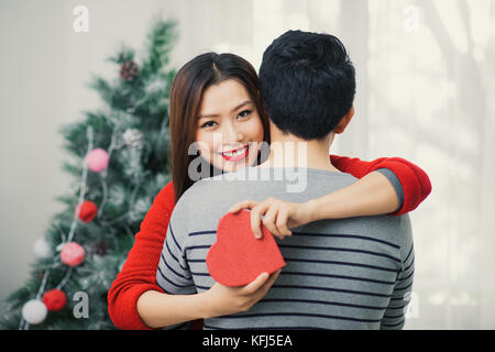 Natale coppia asiatica. Un uomo bello dando la sua fidanzata/moglie un regalo a casa per celebrare il nuovo anno persone Foto Stock