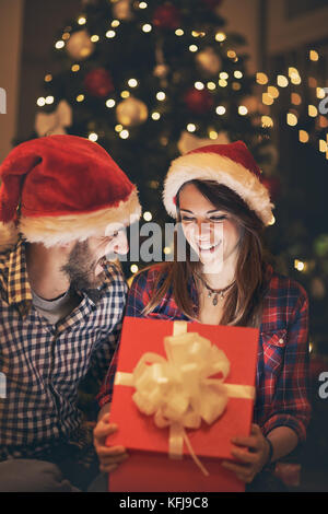 Allegro matura per il nuovo anno a mezzanotte alla ricerca regalo in aprire il riquadro rosso Foto Stock