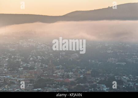 La nebbia mattutina sorge sul centro coloniale e sui monumenti storici della città di San Miguel de Allende, Messico all'alba. Foto Stock