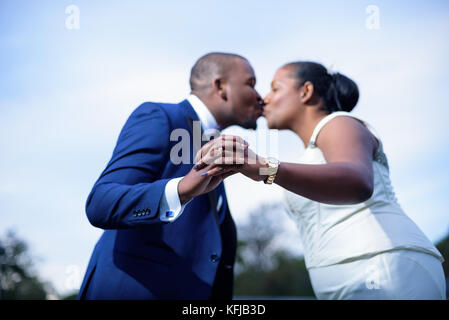 Sposa e lo sposo baciare e mostrando le mani con anelli Foto Stock