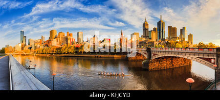 Calda luce dorata sulla città di Melbourne CBD attraverso fiume Yarra dalla southbank tra a piedi ponte pedonale e princes ponte di prima mattina. Foto Stock