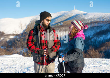 Felice coppia di escursionisti esplorare la montagna innevata in una giornata di sole Foto Stock