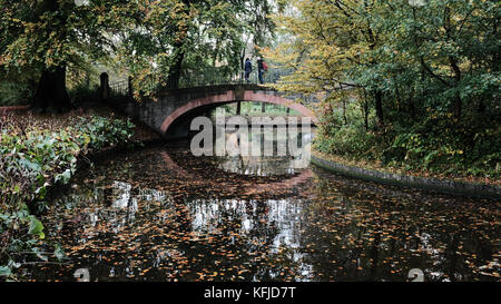 Due escursionisti attraversa un ponte godendo di colori autunnali nei giardini di Frederiksberg, Danimarca Foto Stock