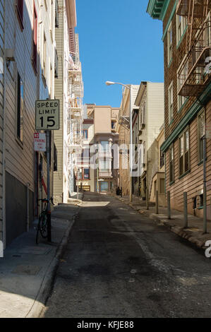 Vuoto, derelitti cercando street, con appartamenti su tutti i lati, contro un cielo azzurro, a San Francisco, California. Vista dal fondo della strada. Foto Stock