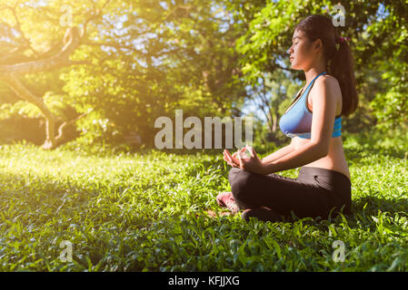 Lo yoga nel parco, outdoor con effetto luce, salute della donna, yoga donna. concetto di uno stile di vita sano e del relax. Foto Stock