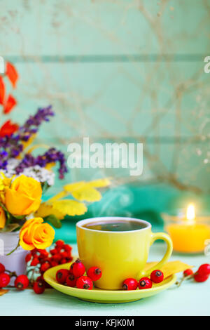 Tazza di caffè, foglie di autunno e fiori su un tavolo di legno. Autunno ancora in vita. Messa a fuoco selettiva. Foto Stock