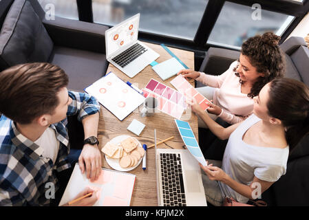 Ragazze aspiranti e uomo seduto e lavorando al tavolo Foto Stock