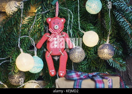 Rosso orso di legno appeso nel ramo di Natale decorato con illuminato palle di Natale Foto Stock