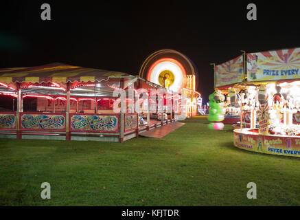 Il viaggio luna park di notte con luci luminose in fiera con illuminato grande ruota panoramica Ferris REGNO UNITO Foto Stock