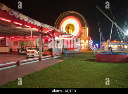 Il viaggio luna park di notte con luci luminose in fiera con illuminato grande ruota panoramica Ferris REGNO UNITO Foto Stock