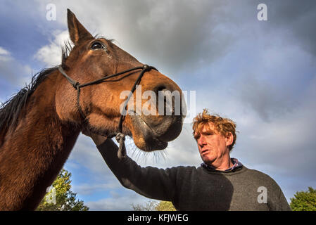 Close up ritratto di cavallo whisperer / equitazione naturale curante tenendo marrone a cavallo all'aperto Foto Stock