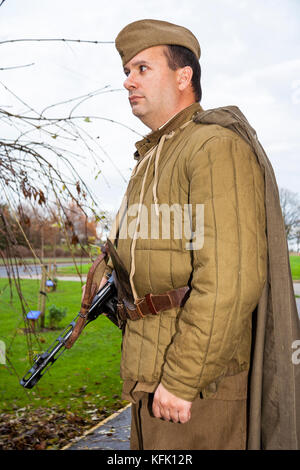 In Inghilterra. Storia viva Re-enactor, vestito nella seconda guerra mondiale la fanteria russa uomo uniforme con burp pistola, PPSh-41. Vista laterale e a basso angolo. Foto Stock