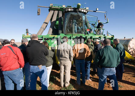 Nuovo trattore John Deere 6 fila raccoglitrice di cotone che rende i moduli rotondo nel campo mentre sotto lo sviluppo di essere visto e studiato dal concessionario John Deere dipendenti Foto Stock