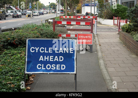 Ciclo chiuso di corsia segno e i ciclisti smontare il segno a lavori per le strade di Richmond, Surrey, Inghilterra Foto Stock