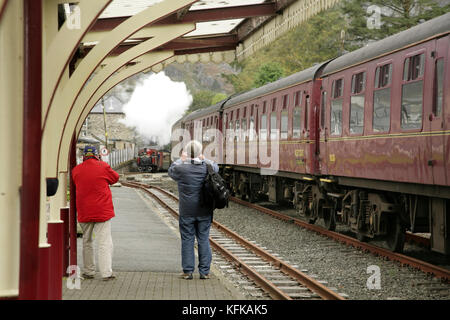 Fotografare persone avvicinando locomotiva a vapore a Blaenau Ffestiniog stazione sul Ffestiniog ferrovia a scartamento ridotto, il Galles. Foto Stock