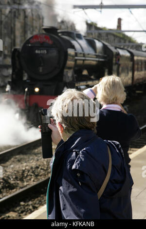 Passeggeri che utilizzano il telefono per fotografare la locomotiva a vapore Scots Guardsman di classe 7P Royal Scot LMS presso la stazione di Carlisle, Regno Unito. Foto Stock