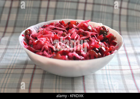 Condimento per insalata in ciotola bianco sul tessuto a scacchi sullo sfondo di close-up. Foto Stock