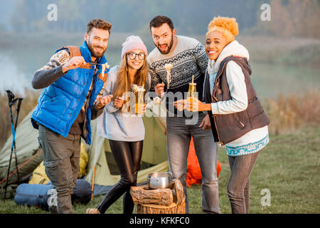 Amici in maglioni fonduta di mangiare all'aperto Foto Stock