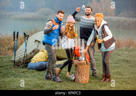 Amici in maglioni fonduta di mangiare all'aperto Foto Stock