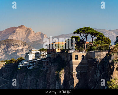 Cliff edge Grand Hotel Riviera con paesaggio di montagna in background e pietra di alberi di pino in primo piano. Sorrento. L'Italia. Foto Stock