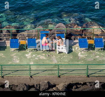 Vista aerea della spiaggia privata con un paio di mangiare mentre seduti su sedie a sdraio. Sorrento. L'Italia. Foto Stock