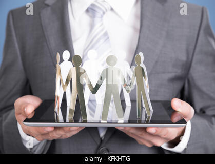 Imprenditore azienda persone di carta sul tablet. Closeup shot Foto Stock