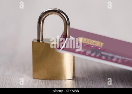 Vista dettagliata del lucchetto attaccato alla carta di credito sul tavolo di legno Foto Stock