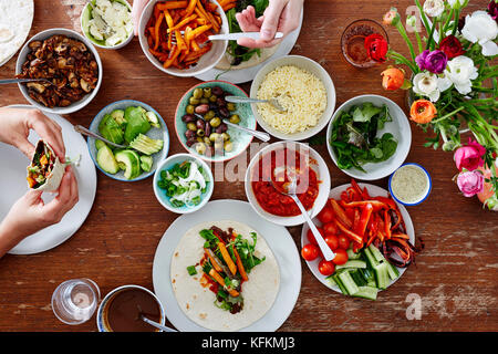 Due persone godendo di avvolgimenti a spago e di fingerfood e cena con gli amici Foto Stock