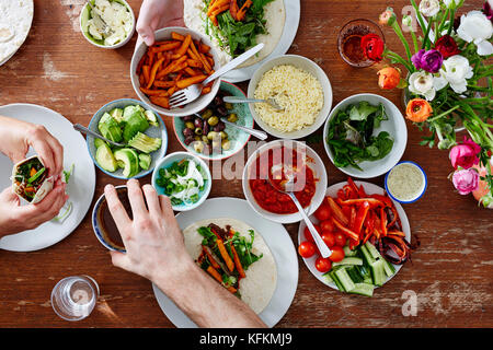 Tre amici a cena informale delle parti sane e avvolge fingerfoods sani Foto Stock