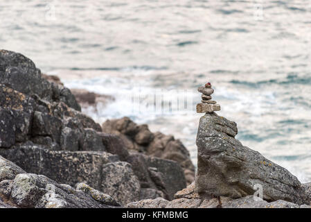 Impilamento di rocce - piccole rocce impilate e bilanciate su una grande roccia a Porth Nanven Cornwall. Foto Stock