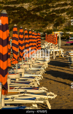 Lettini e ombrelloni sulla spiaggia. Peschici e il Parco Nazionale del Gargano. L'Italia. Foto Stock