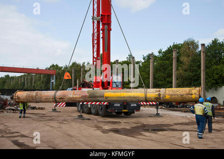 Il tubo offshore fuori servizio viene sollevato da una gru nel deposito di rottami metallici dopo la consegna con camion dai bacini di Great Yarmouth. Foto Stock