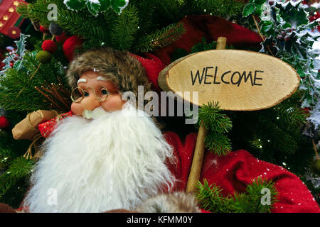 Santa Claus figura, Decorazione per albero di natale, tenendo un consiglio la lettura di benvenuto. Close up Foto Stock