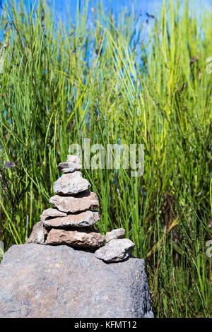 Una pila di rocce equilibrate con erba alta nel sfondo Foto Stock