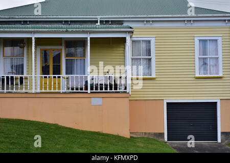 Vecchia casa con un pallido giallo rivestimento in legno e metallo tetto ondulato. Foto Stock