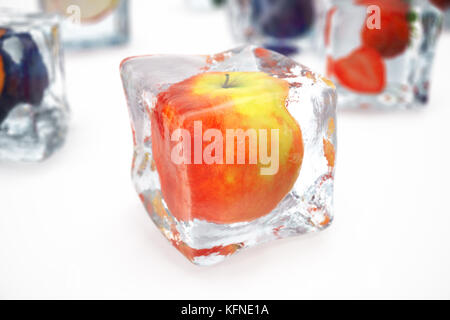 Apple nel cubo di ghiaccio isolato su bianco con effetti di profondità di campo. cubetti di ghiaccio con frutti di bosco freschi. bacche frutti congelati in cubetti di ghiaccio, rendering 3D Foto Stock