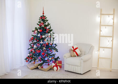 Albero di natale in una camera bianca con un saluto di Natale regali Foto Stock