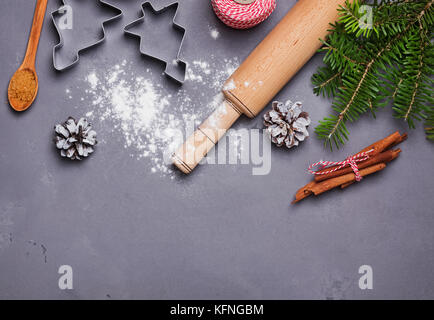 Far Natale cookie: roling pin, farina, di spezie e di Abete rami sullo sfondo grigio Foto Stock