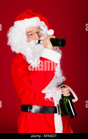 Santa bere birra su sfondo rosso Foto Stock